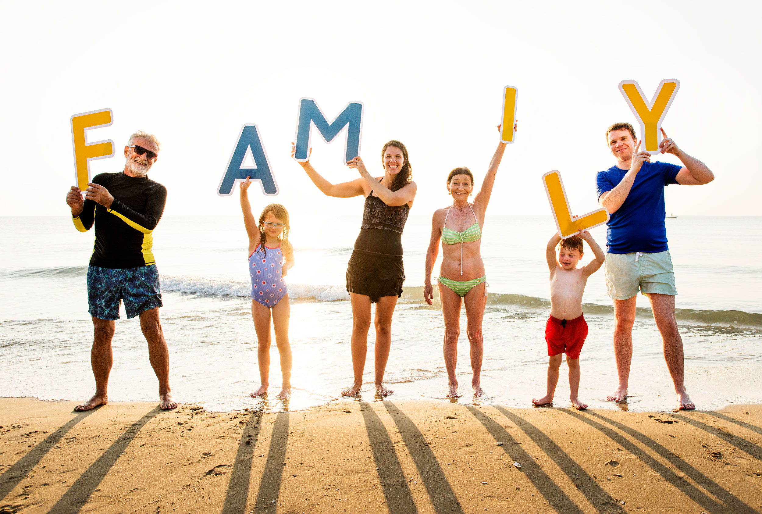 Family holding up letters that spell FAMILY on a beach